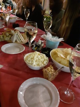 A picture of an "aperitivo" with wine, chips, nuts, pizza and popcorns