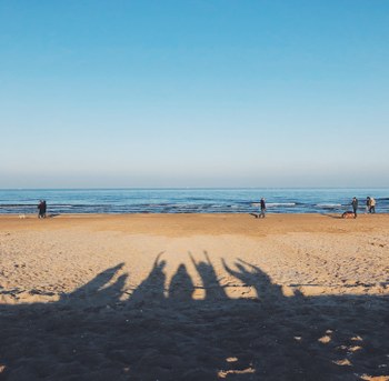 A sandy beach at sunset with people casting shadows onto the sand