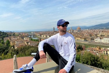 Adrien sitting on a rooftop overlooking the city of Florence.
