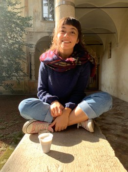 Idil sitting in a courtyard while having a cup of coffee